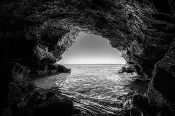 Melancholisch wirkendes Foto einer Höhle mit ins Meer fließendes Wasser