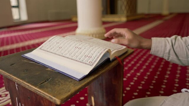 Islamic prayer concept Muslim man carefully studies the Holy Quran and prays to Allah in the mosque