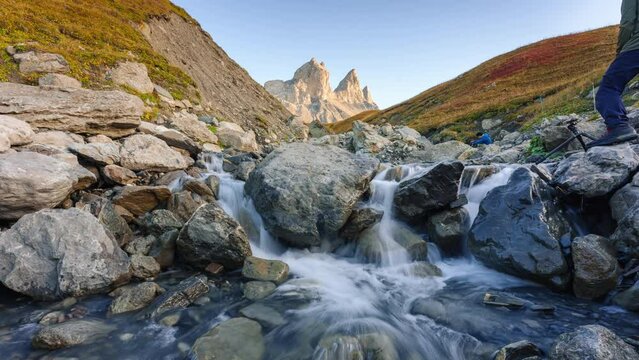 Landscape iconic three peak mountain with waterfall flowing and tourist taking pictures in valley of Aiguilles d Arves in French alps on autumn at Savoie, France