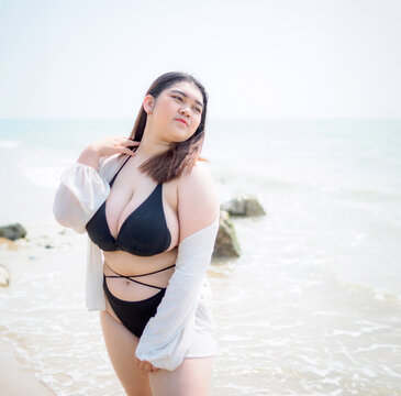 Portrait young woman asian chubby fat cute beautiful one person in bikini black sexy frontview tropical sea beach white sand clean and blue sky background calm nature ocean wave water travel fun happy