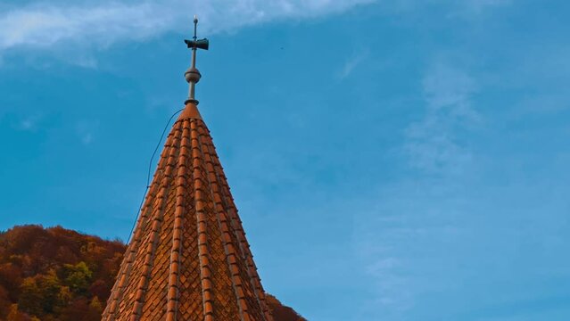 Tower with red tiling on the pointed roof. View of the top of Bran castle in Romania. Colorful nature at backdrop.