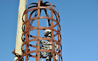 Fake human skeleton hanging inside a metal cage, punishment from the middle ages
