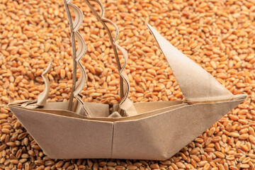 A sailboat or origami boat on a background of wheat grain. Concept of grain deal and world food...
