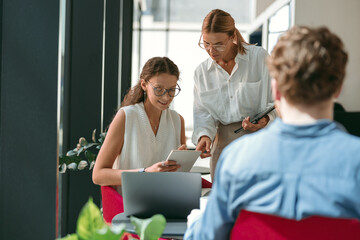 Female boss shows something in notebook to employee during working day in office