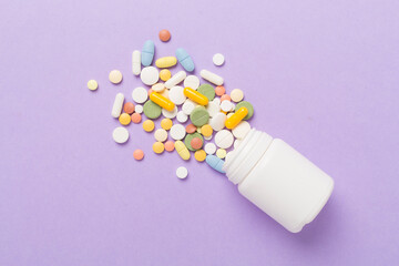 Jar with different medical pills and capsules on color background, top view