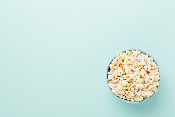 Tasty popcorn in bowl on color background, top view