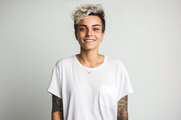 Gender non-binary adult teenager with tattoos looking at the camera on a light background.  - obrazy, fototapety, plakaty