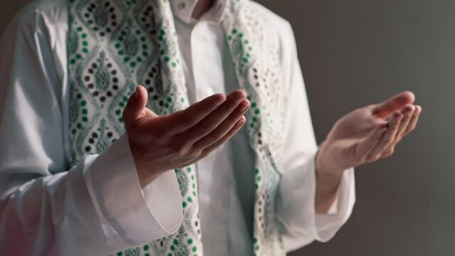 Close-up shot of a Muslim man's hands praying on his knees during Ramadan in Islamic temple