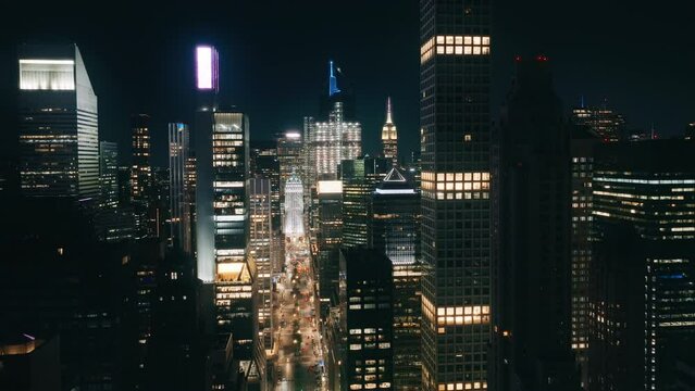 Scenic view of urban canyon street road on Manhattan with busy car traffic. Cinematic city lights at dark night. NYC illumination. Aerial birds eye perspective of New York City skyscrapers at night 4K