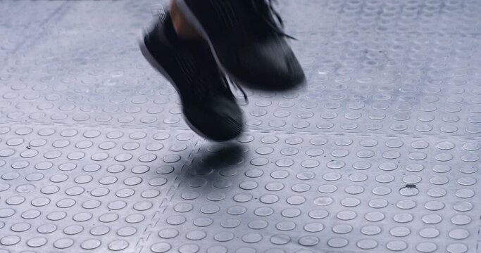 Feet, person and jump with rope in gym for cardio, workout and training for energy, exercise challenge and power. Closeup, shoes of athlete and skipping for sports, fitness and performance of action