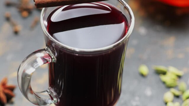 Mulled wine glass with cinnamon stick on wooden table. Tilt up camera movement