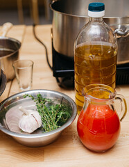 Tomato juice in a glass jug, bottle of sunflower oil, garlic, thyme on a wooden table. Raw foods before cooking.