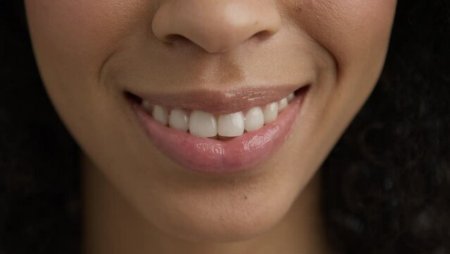 Lips kiss in natural day light. Beauty sexy female model with dark skin and full glossy pink lips closeup. Woman mouth slow motion. Perfect soft skin sexy multi racial diverse model smiling kiss 4K