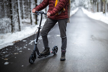 Adult Carefree Caucasian Woman Riding a Kick scooter on Winter Forest Environment Road