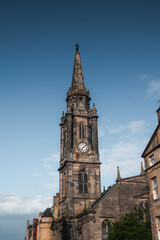 Fototapeta na wymiar Tower of old church in Edinburgh, Scotland old town against blue sky. Medieval architecture