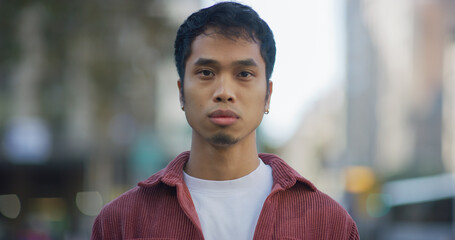 Young Filipino man serious face portrait on city street - obrazy, fototapety, plakaty
