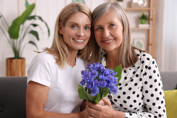 Fototapeta na wymiar Happy mature mother and her daughter with beautiful cornflowers at home