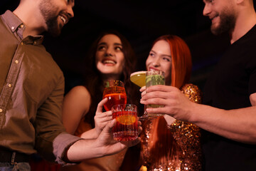 Friends clinking glasses with fresh cocktails in bar, selective focus