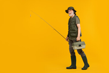 Fisherman with rod and box for fishing tackle on yellow background, space for text