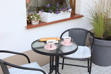 Cups of coffee, bread and cheese on glass table. Relaxing place at outdoor terrace
