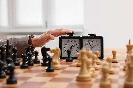 Man turning on chess clock during tournament at chessboard, closeup
