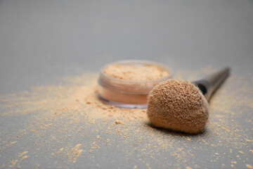 Fototapeta na wymiar Loose face powder and makeup brush on light grey background, closeup. Space for text