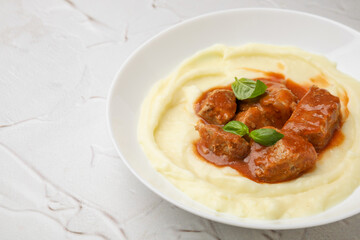 Delicious goulash with mashed potato on white textured table, closeup