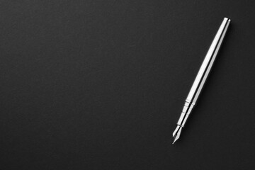Stylish silver fountain pen on black background, top view. Space for text