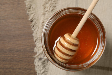 Dipper with honey in jar on wooden table, top view. Space for text