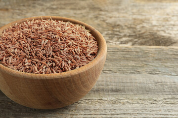 Bowl of caraway seeds on wooden table, closeup. Space for text
