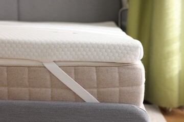 White memory foam mattress topper on grey bed, closeup