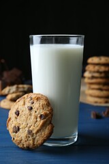 Tasty chocolate chip cookies and glass of milk on blue wooden table