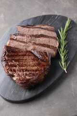 Delicious fried beef meat with rosemary on grey textured table
