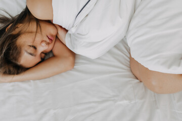 Asian woman sleeping on white bed in concept of tried and drunk morning.
