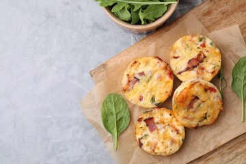 Delicious egg muffins with cheese and bacon on grey table, flat lay. Space for text