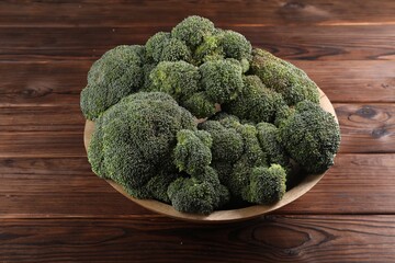 Bowl of fresh raw broccoli on wooden table