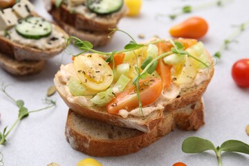 Tasty vegan sandwiches with vegetables on light grey table, closeup