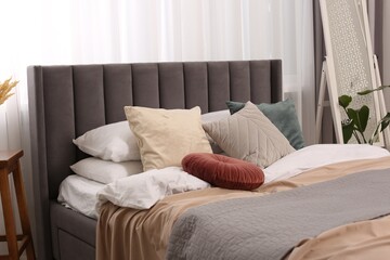 Fototapeta na wymiar Large comfortable bed with soft pillows and blankets in room. Home textile