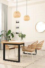 Stylish dining room with cozy furniture, mirror and plants