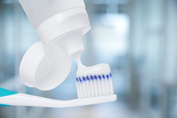 Squeezing toothpaste onto toothbrush against blurred background