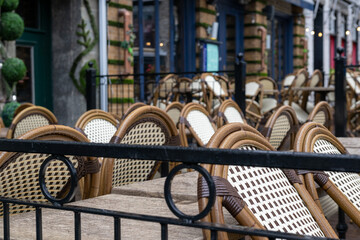The exterior seating area of an empty restaurant or bistro. The tables are in rows with rattan...