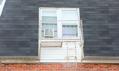 fire escape staircase zigzags outside a brick building, representing escape routes, emergency...