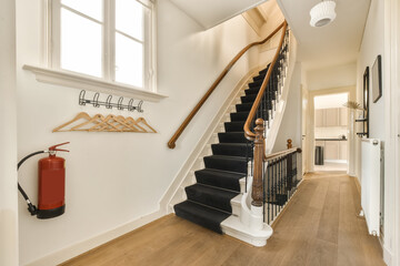 a staircase in a house with wood flooring and white trim on the stairs, there is a red fire exor