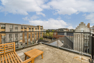 a balcony with two wooden benches and a bench on the left side, looking out at buildings in the...