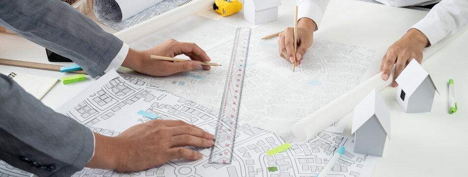 Worker, architect and engineer work on real estate construction project oratory planning with cartography and cadastral map of urban town area to guide to construction developer business plan of city