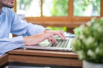 Close-up freelance businessman working at indoors home office typing hand on desk computer laptop...