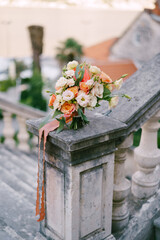 Obraz na płótnie Canvas Bridal bouquet stands on the stone handrail of an ancient balustrade in the garden