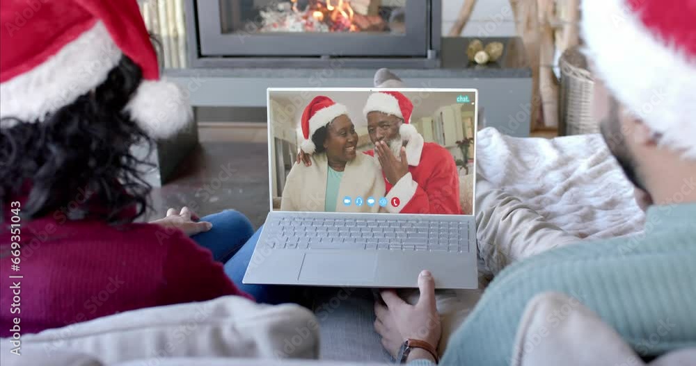 Wall mural Happy diverse couple and senior parents having christmas laptop video call, slow motion