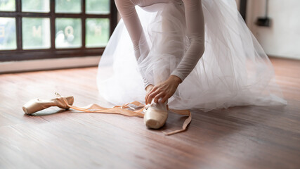 Ballerina in ballet shoes. Asian girl tying ribbons of toe shoes. ballet dancer preparing and wearing ballet shoes in dance studio prepares for a rehearsal.