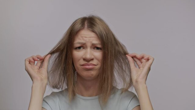 A woman shows her thin bad hair. Thinning and hair loss. Emotional disorders